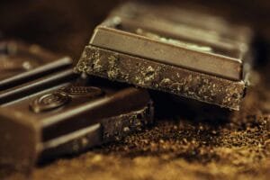 chocolate-dark-coffee-confiserie-65882-65882-1 Macro shot of rich dark chocolate bars sprinkled with cocoa powder, highlighting texture and indulgence.